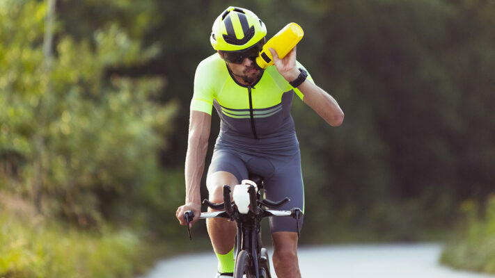 Triathlete drinking electrolyte mix during bike leg of triathlon.
